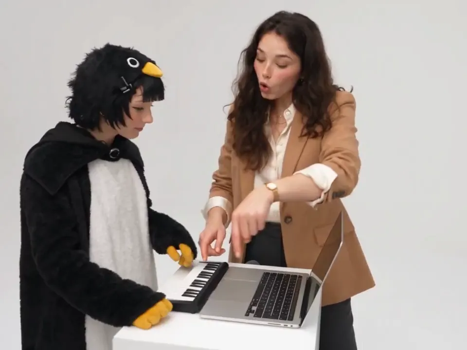 The Studio Sketch scene: white backdrop, a desk with a laptop and mini keyboard, and two people ready to play
